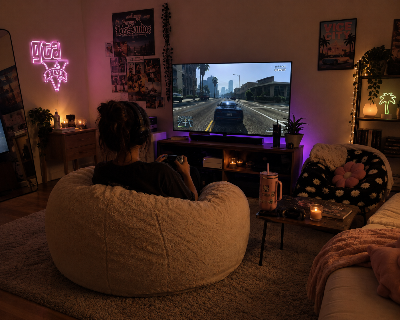 A person sits in a beanbag in a darkened den at night, controller in hand, playing Grand Theft Auto on a large TV. A neon GTA V sign glows on the wall above.